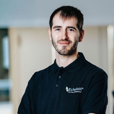 Porträt eines Mitarbeiters von mIT solutions im EcholoN Shirt mit verschränkten Armen, der selbstbewusst in die Kamera blickt