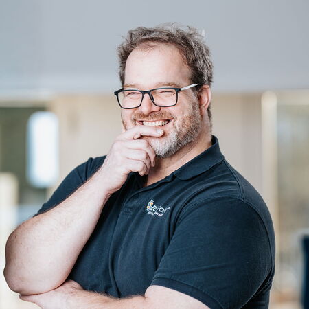Porträt eines Mitarbeiters von mIT solutions im EcholoN Shirt, der lächelnd und selbstbewusst in die Kamera blickt