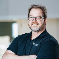 Porträt eines Mitarbeiters von mIT solutions im EcholoN Shirt mit verschränkten Armen, der freundlich und souverän in die Kamera blickt